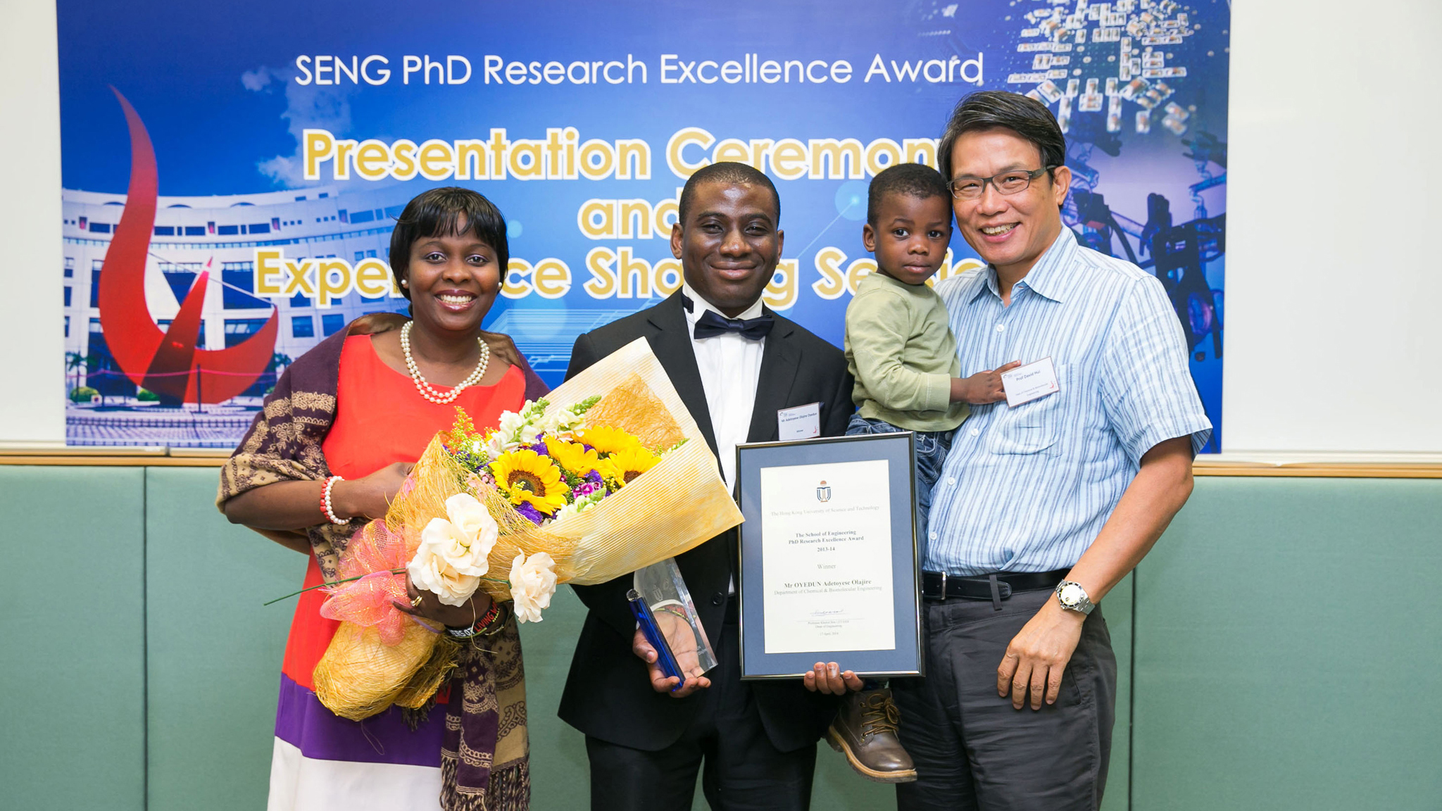 Ade poses for a photo with his beloved family and his supervisor Prof. David HUI (right) at the 2014 HKUST School of Engineering PhD Research Excellence Award Ceremony, where he received an award.