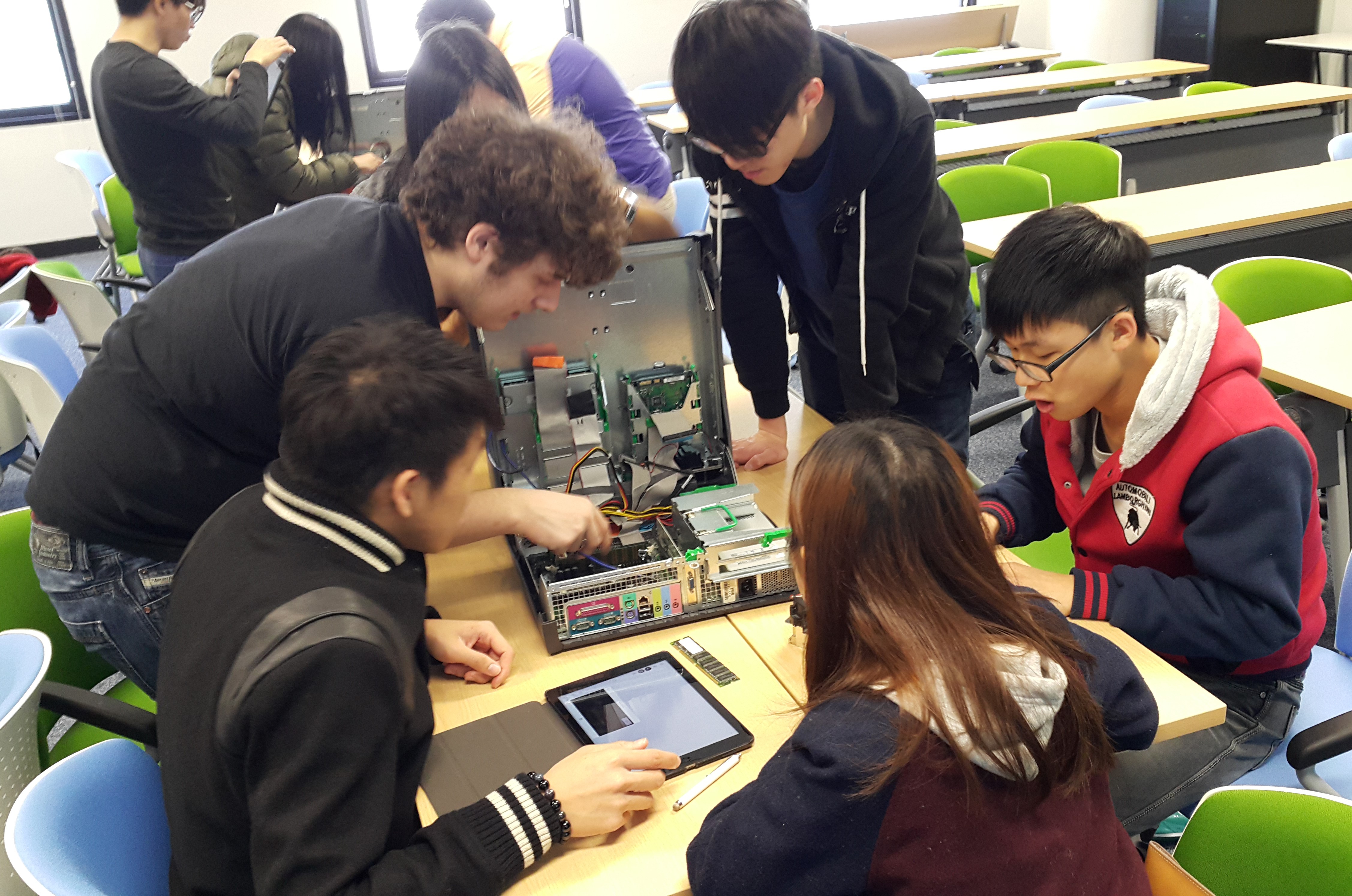 Students work in teams to identify hardware components inside a desktop computer. WYSIWYG (What-you-see-is-what-you-get) is achieved by directly touching and investigating the insides of the computer.