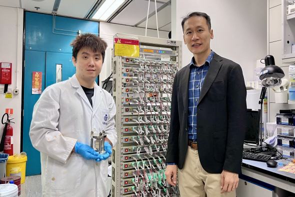 Prof. Kim Yoonseob (right), Associate Professor in the Department of Chemical and Biological Engineering and the study’s corresponding author, stands with his PhD student Gu Muhua (left), the paper’s first author, who is holding a solid-state battery cell mold. They are pictured beside a battery cell cycler.