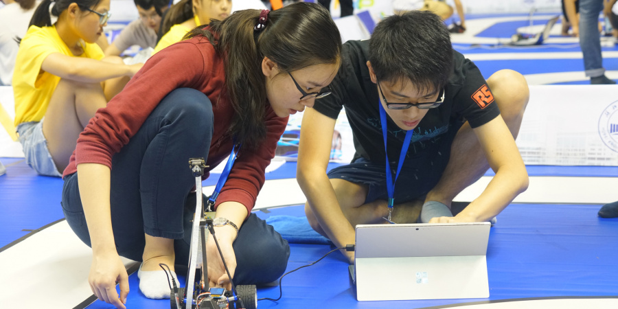 Two students from the 4-member First Class Award-winning team prepare their smart car in the competition.	