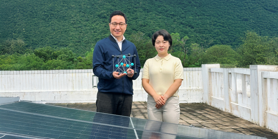 Corresponding author Prof. Zhou Yuanyuan (left), holding a crystal model of perovskite, and first author Dr. Duan Tianwei (right) standing in front of solar panels.