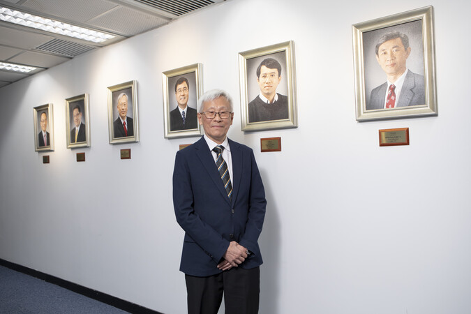 Prof. Philip Chan outside the Office of the Dean of Engineering, in front of the photos of all former Deans, including his own.