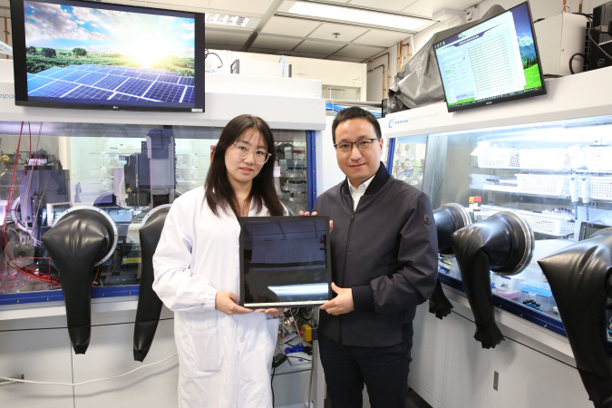 Prof. Zhou Yuanyuan (right), corresponding author of the study, and Dr. Hao Mingwei (left), co-first author of the study, hold a perovskite solar panel made with the “slow-release solvent” strategy.