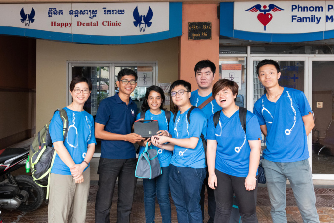 周教授和視野無界MedEasy的隊員在One-2-One辦公室門前向職員講解MedEasy的伺服器。One-2-One是柬埔寨當地的非政府組織，亦是視野無界成立後首批合作夥伴之一。該項目贏得2016年萊斯360°第六届本科生全球健康科技設計比賽第一名。