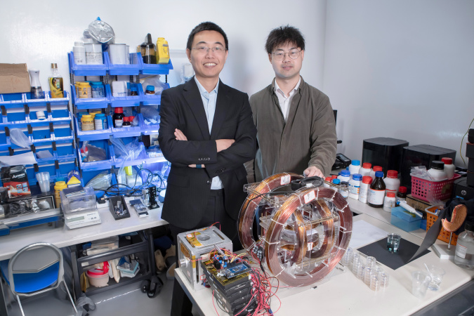 Prof. Shen Yajing (left) and co-first author Dr. Yang Xiong (right) with the magnetic actuation platform for microswimmer control in front.