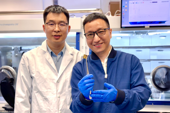 The lead corresponding author Prof. Zhou Yuanyuan (right) and co-first author Dr. Guo Pengfei (left) are showing a perovskite solar cell prototype made for a proof-of-concept demonstration of the novel laminate-structured interface.