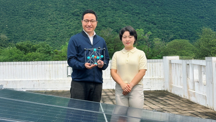 Corresponding author Prof. Zhou Yuanyuan (left), holding a crystal model of perovskite, and first author Dr. Duan Tianwei (right) standing in front of solar panels.