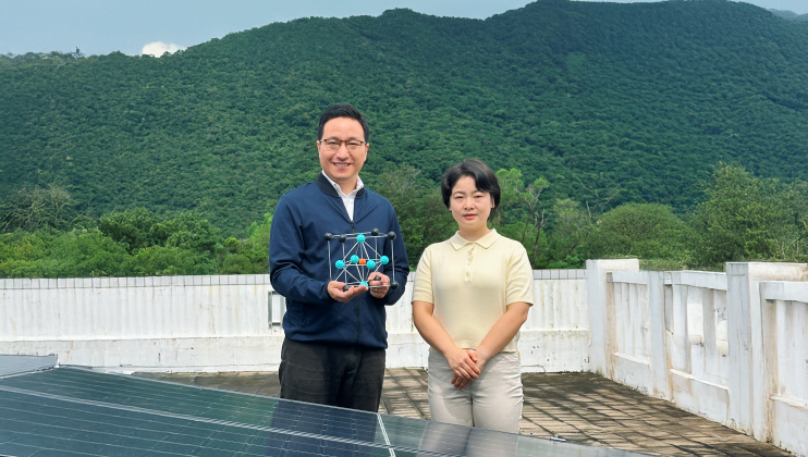 Corresponding author Prof. Zhou Yuanyuan (left), holding a crystal model of perovskite, and first author Dr. Duan Tianwei (right) standing in front of solar panels.
